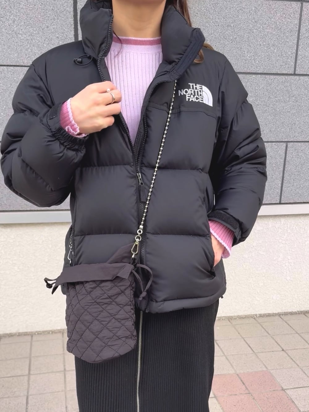 ブラック系のダウンジャケット/コート、ピンク系のニット/セーター、ブラック系のスカートを着用したレディースの冬コーディネートの2枚目の写真