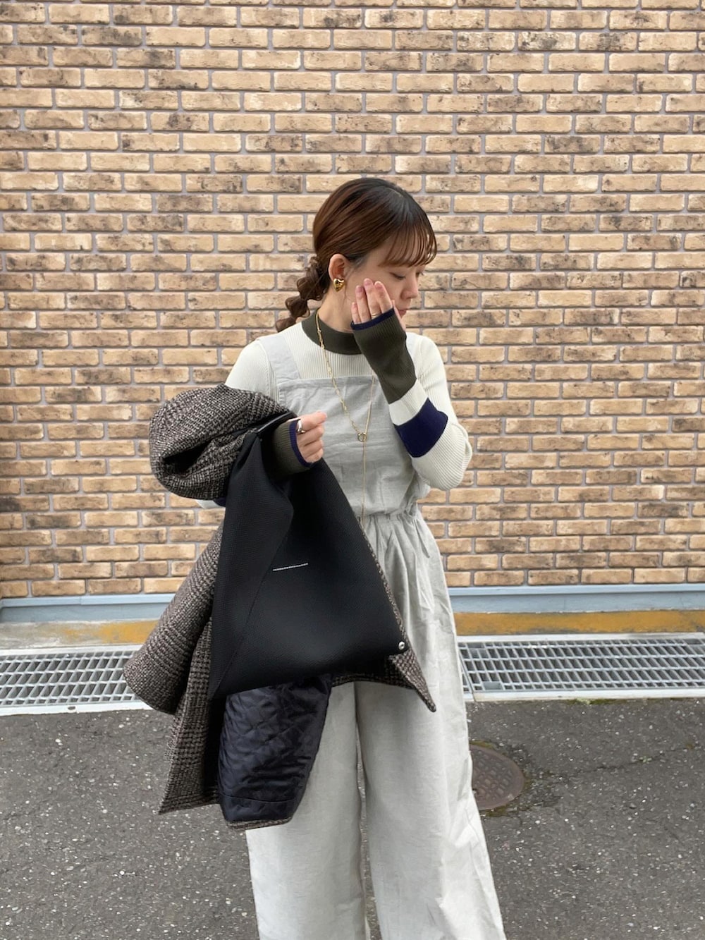 グレー系のサロペット/オーバーオール、ホワイト系のニット/セーター、ブラック系のトートバッグを着用したレディースの冬コーディネートの2枚目の写真