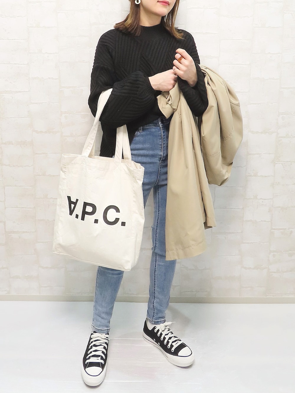 ブラック系のニット/セーター、ベージュ系のトレンチコート、ブルー系のデニムパンツを着用したレディースの冬コーディネートの3枚目の写真