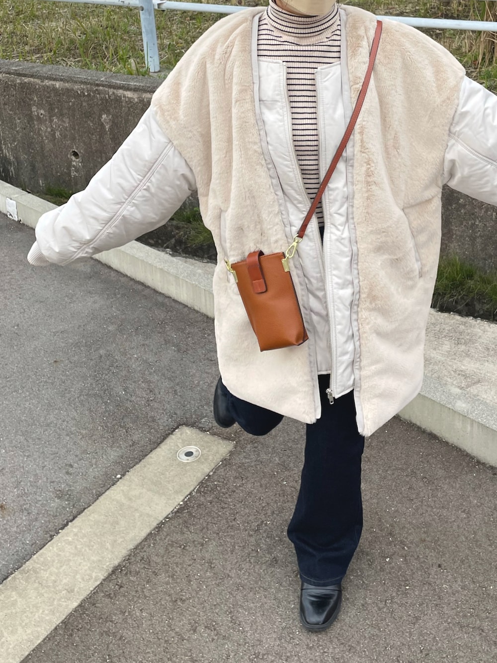 ベージュ系のブルゾン、ホワイト系のニット/セーター、ブルー系のデニムパンツを着用したレディースの冬コーディネートの4枚目の写真