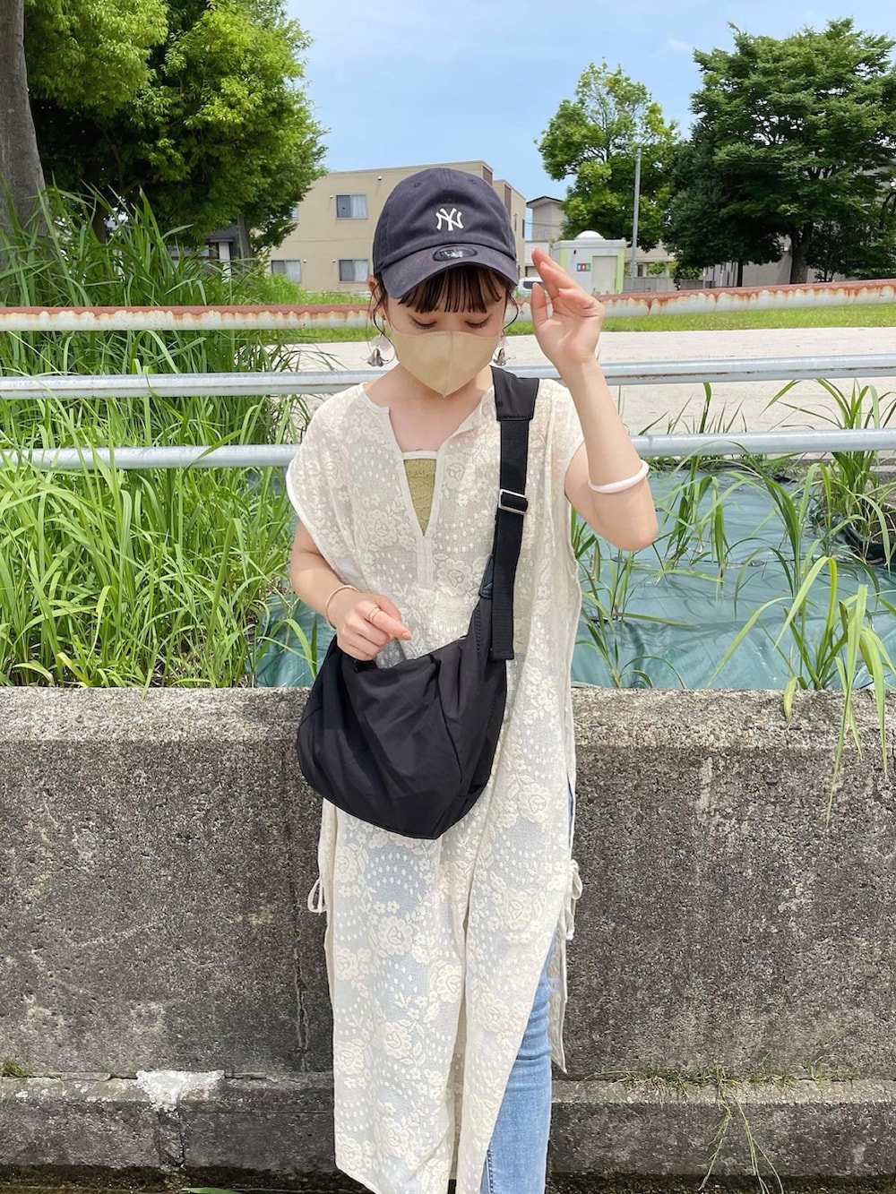ホワイト系のワンピース、ブラック系のショルダーバッグ、ブラック系のサンダルを着用したレディースの夏コーディネートの2枚目の写真