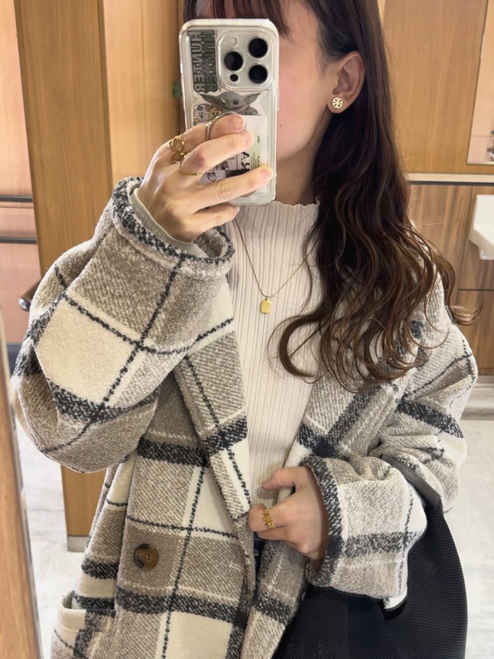 ホワイト系のチェスターコート、ブラック系のスニーカー、ブラック系のトートバッグを着用したレディースの冬コーディネートの3枚目の写真