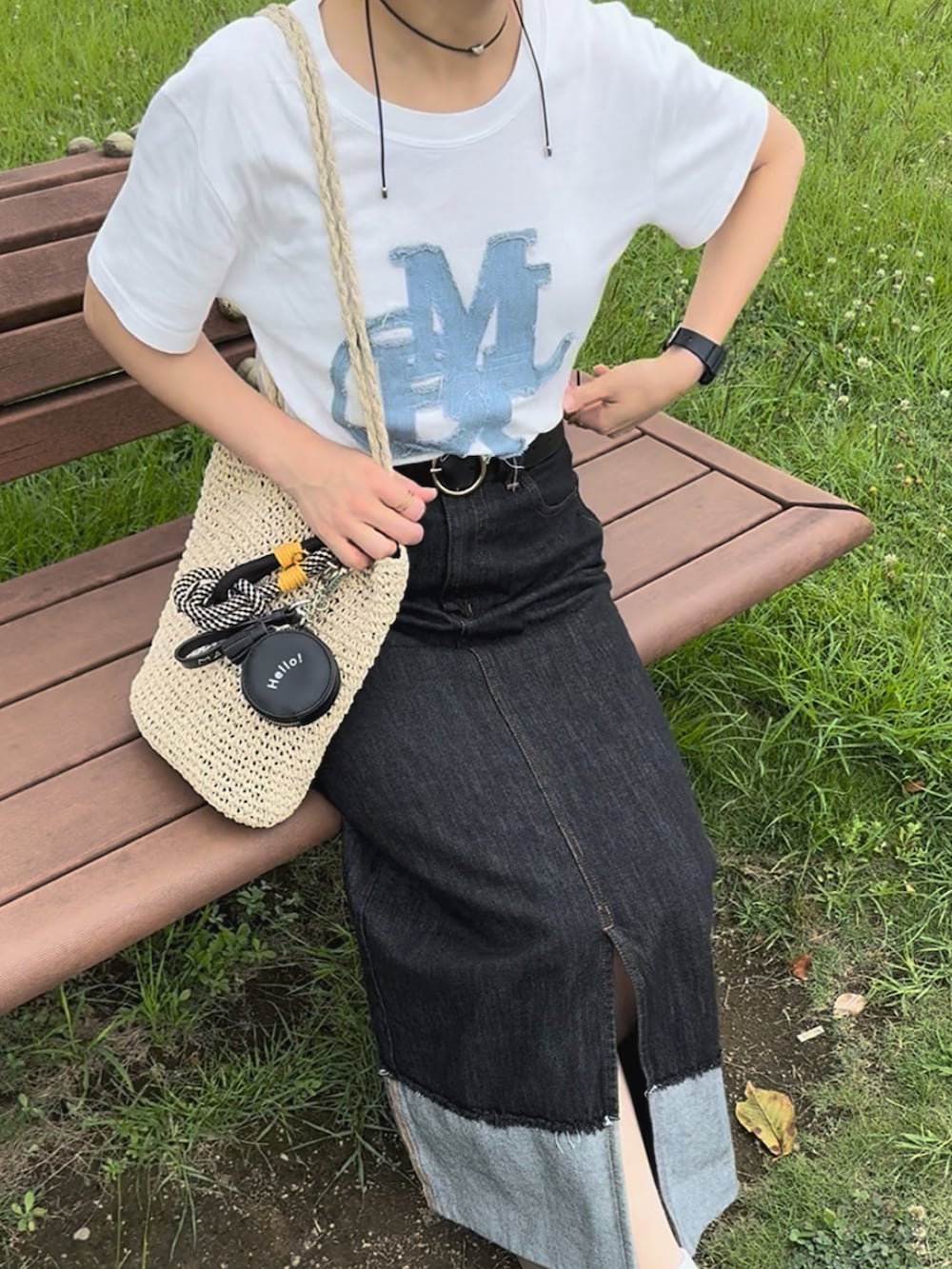 ホワイト系のTシャツ/カットソー、ブラック系のデニムスカート、ベージュ系のかごバッグを着用したレディースの夏コーディネートの2枚目の写真