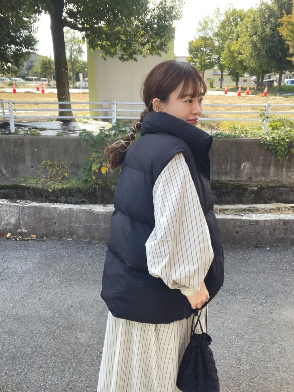 ブルー系のワンピース、ブラック系のベスト、ブラック系のブーツを着用したレディースの秋コーディネートの2枚目の写真