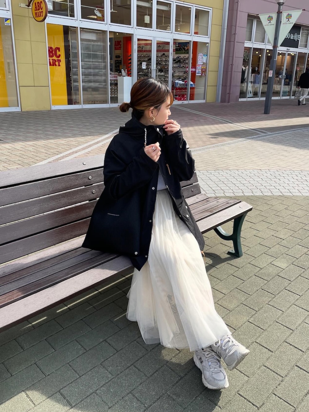 ブラック系のマウンテンパーカー、ホワイト系のTシャツ/カットソー、ホワイト系のスカートを着用したレディースの春コーディネートの3枚目の写真