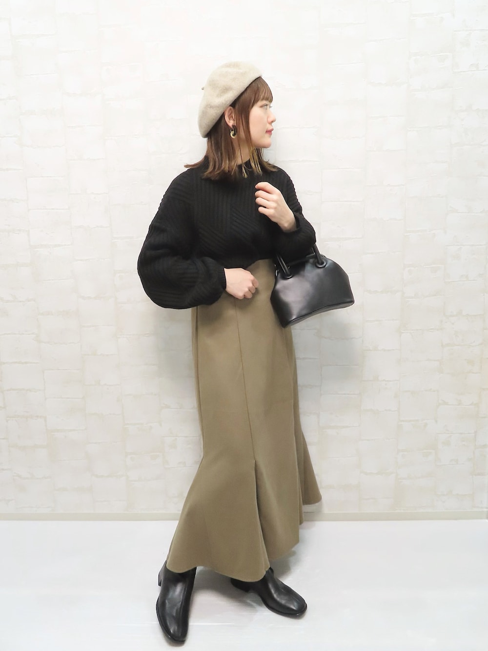 ブラック系のニット/セーター、ベージュ系のスカート、ブラック系のボストンバッグを着用したレディースの冬コーディネートの2枚目の写真