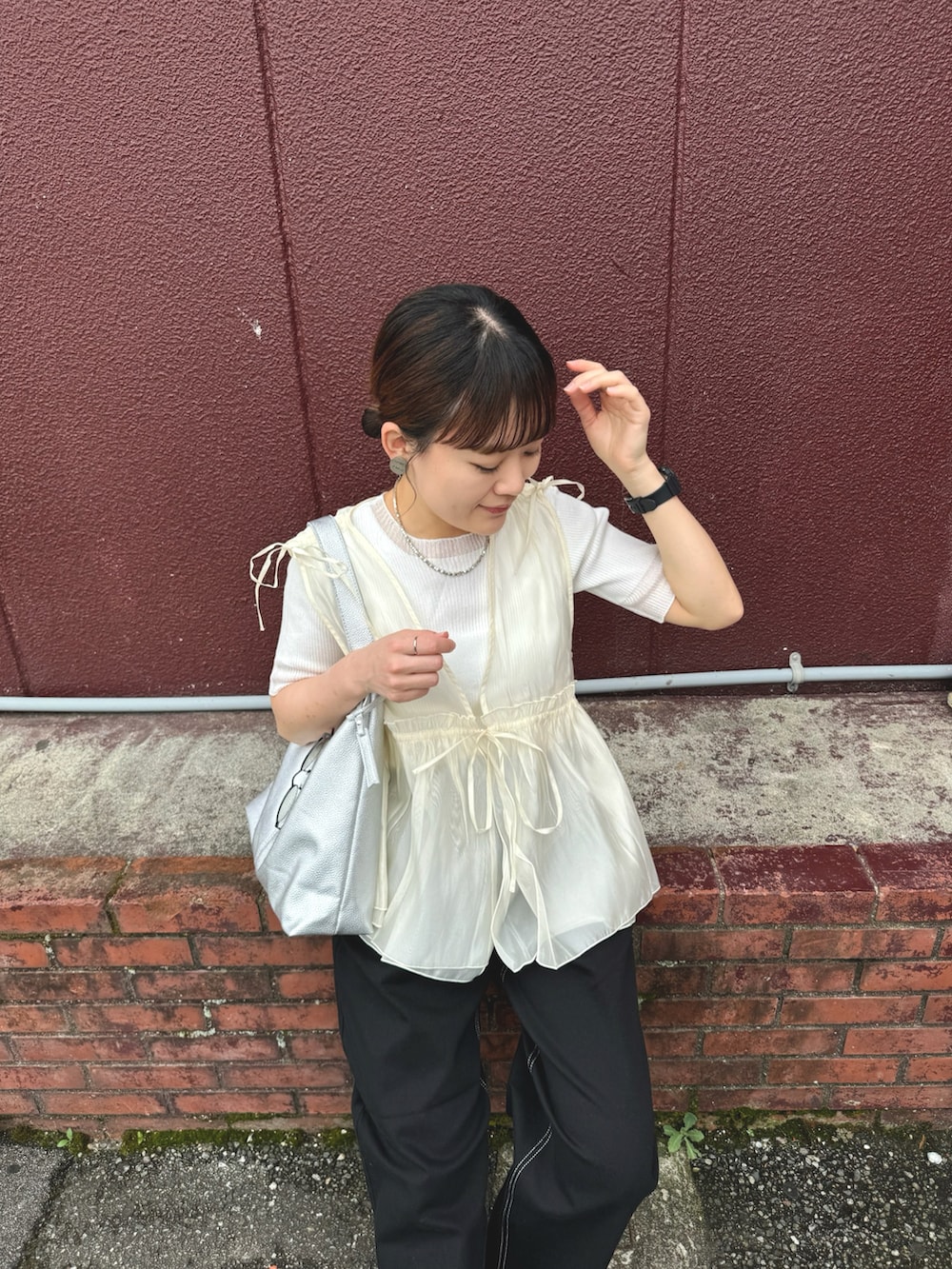 ホワイト系のニット/セーター、ブラック系のデニムパンツ、シルバー系のトートバッグを着用したレディースの夏コーディネートの5枚目の写真