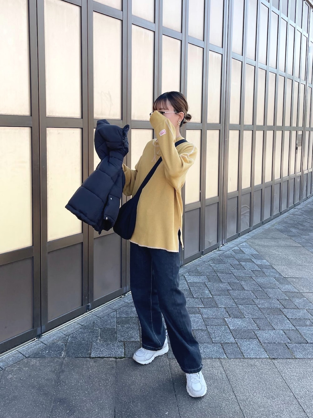 ブラック系のダウンベスト、イエロー系のTシャツ/カットソー、ブラック系のデニムパンツを着用したレディースの冬コーディネートの2枚目の写真