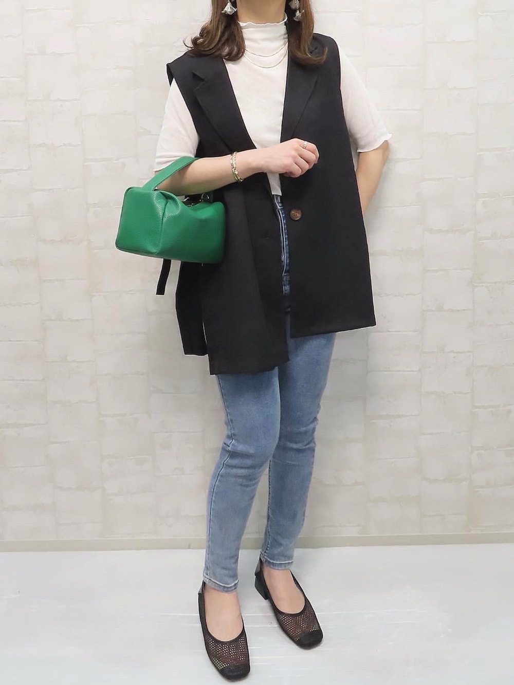 ブラック系のベスト、ホワイト系のTシャツ/カットソー、グリーン系のショルダーバッグを着用したレディースの春コーディネートの2枚目の写真