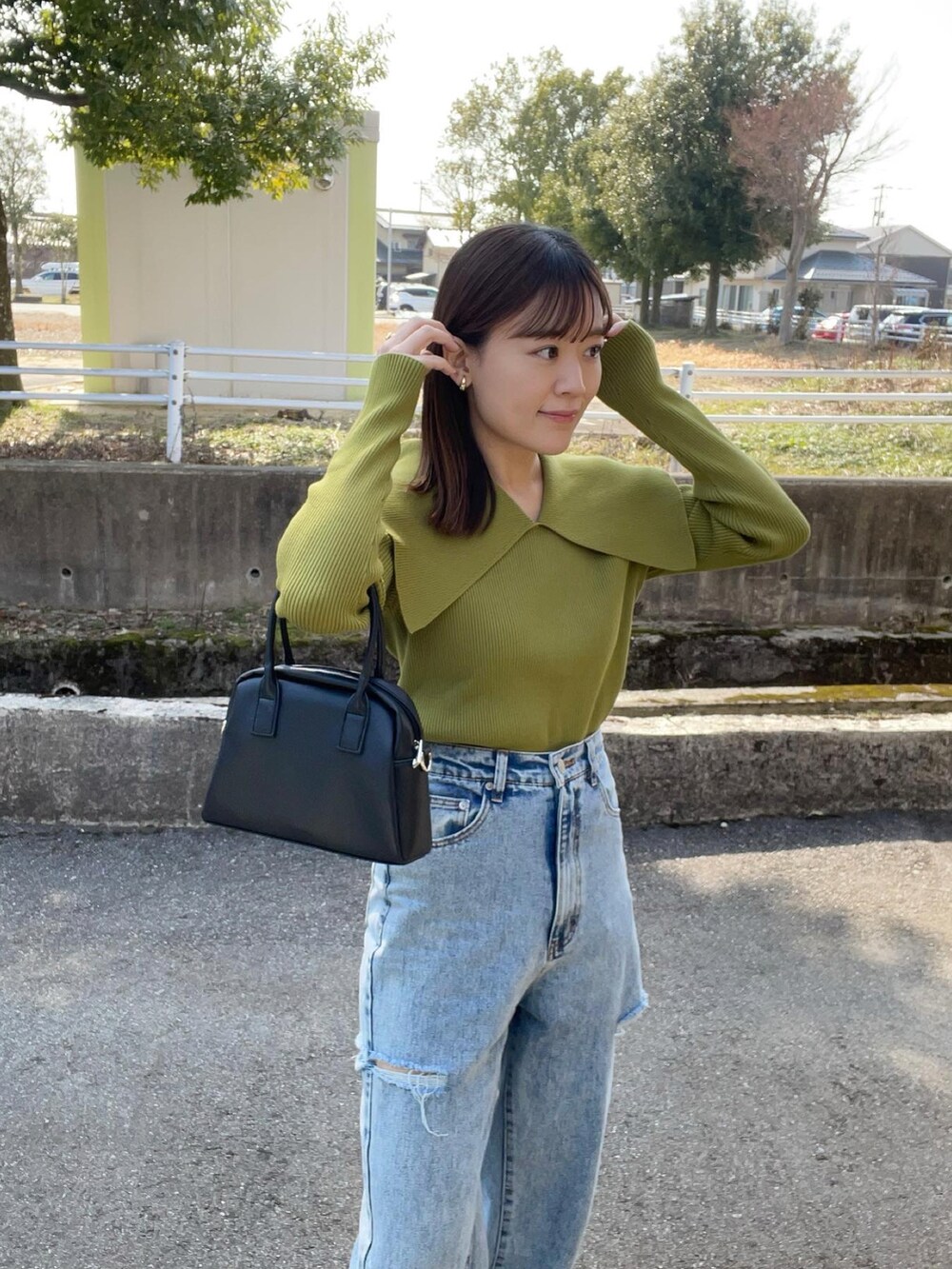 グリーン系のニット/セーター、その他のデニムパンツ、ブラック系のボストンバッグを着用したレディースの春コーディネートの5枚目の写真