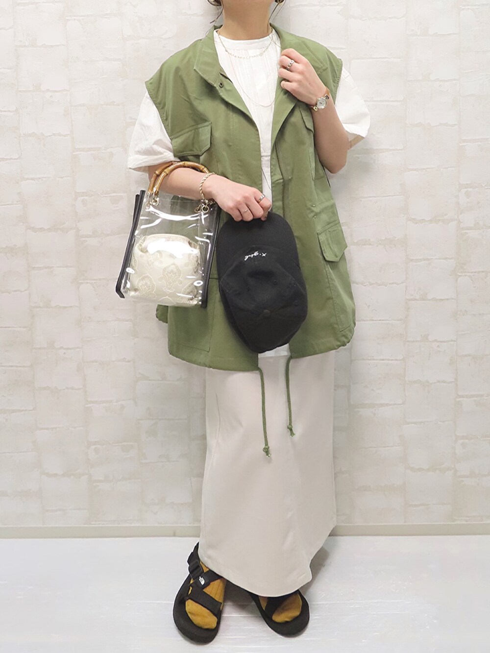 グリーン系のベスト、ホワイト系のシャツ/ブラウス、ホワイト系のスカートを着用したレディースの夏コーディネートの3枚目の写真