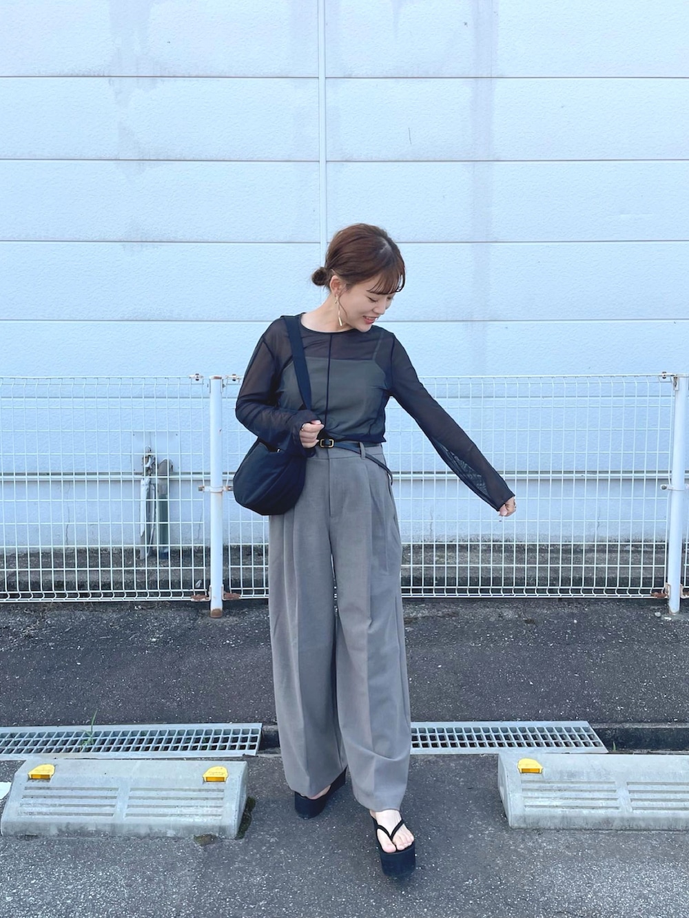ブラック系のトップス、ブラウン系のパンツ、ブラック系のショルダーバッグを着用したレディースの夏コーディネートの4枚目の写真