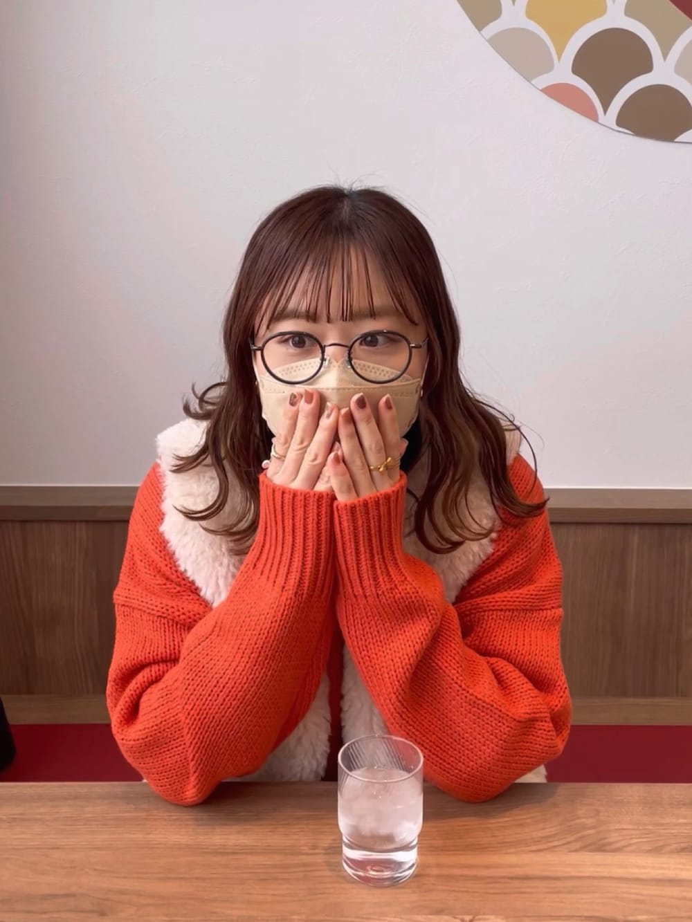 オレンジ系のカーディガン/ボレロ、グレー系のベスト、ブラック系のデニムパンツを着用したレディースの冬コーディネートの3枚目の写真