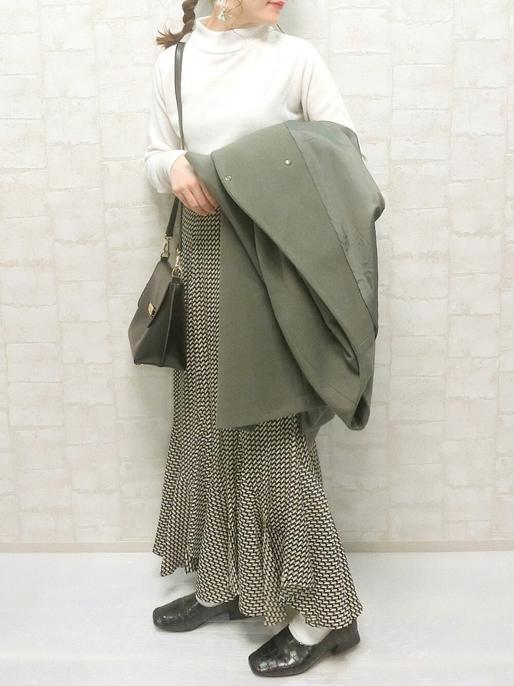 ブラック系のスカート、ホワイト系のニット/セーター、グリーン系のノーカラーコートを着用したレディースの秋コーディネートの2枚目の写真