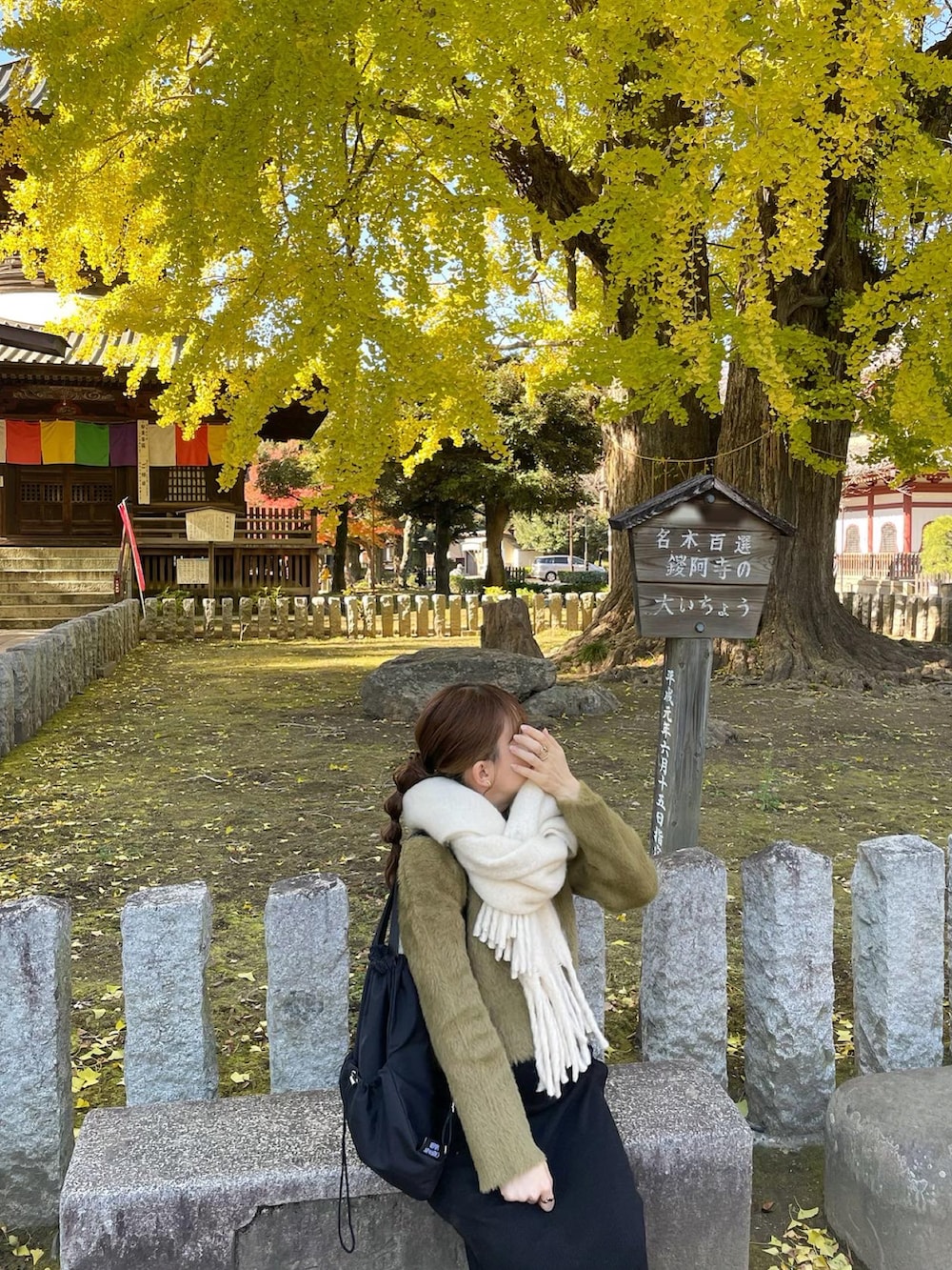 グリーン系のニット/セーター、ブラック系のバックパック/リュック、ホワイト系のスニーカーを着用したレディースの秋コーディネートの2枚目の写真