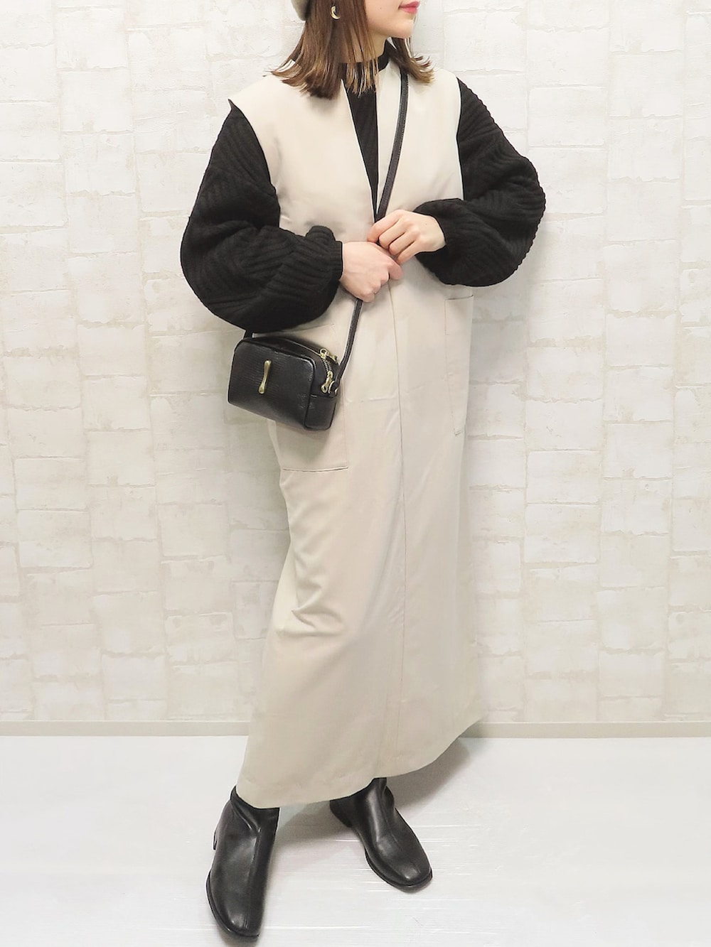 ブラック系のニット/セーター、ベージュ系のワンピース、ブラック系のショルダーバッグを着用したレディースの冬コーディネートの2枚目の写真