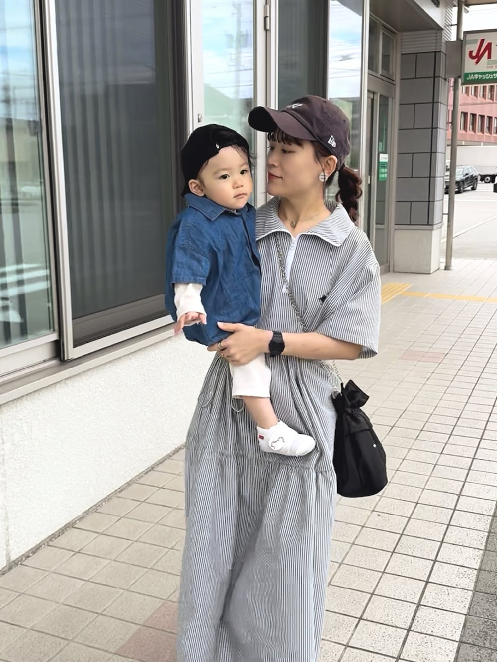 ブラック系のワンピース、ホワイト系のスニーカー、ブラック系のショルダーバッグを着用したレディースの夏コーディネートの3枚目の写真