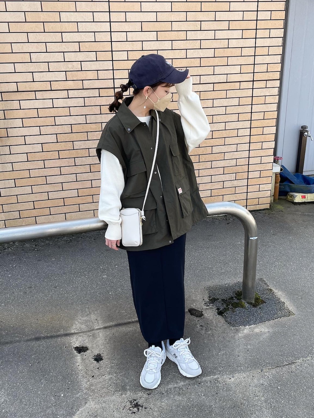 グリーン系のマウンテンパーカー、ホワイト系のニット/セーター、ブラック系のスカートを着用したレディースの春コーディネートの2枚目の写真