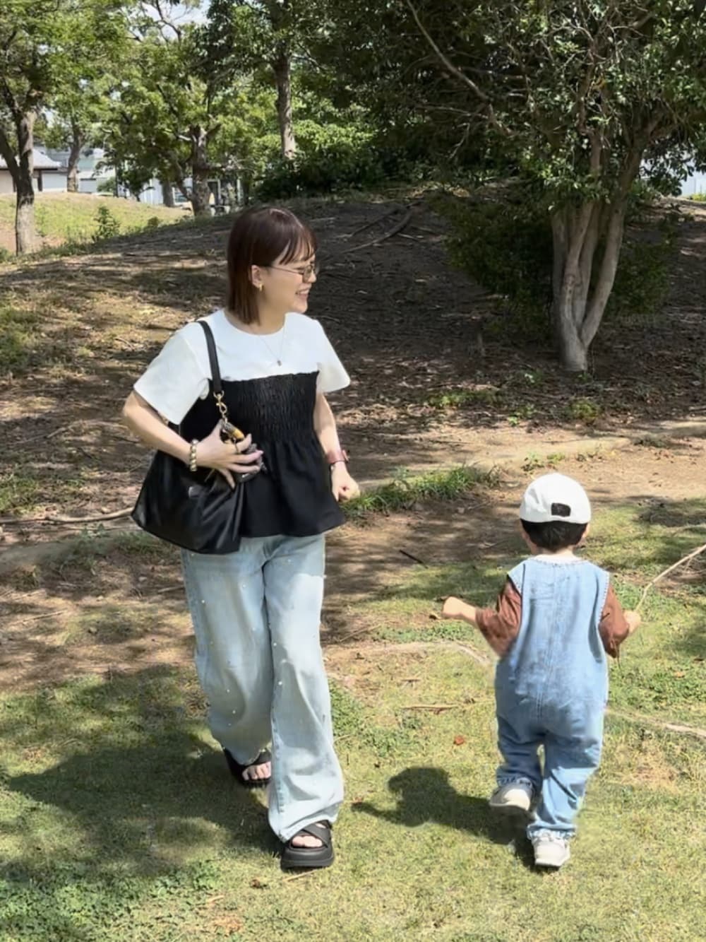 ホワイト系のTシャツ/カットソー、ブルー系のデニムパンツ、ブラック系のバッグを着用したレディースの夏コーディネートの2枚目の写真