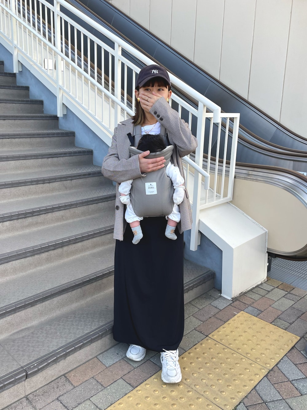 ブラウン系のテーラードジャケット、ブラック系のワンピース、ホワイト系のスニーカーを着用したレディースの冬コーディネートの4枚目の写真