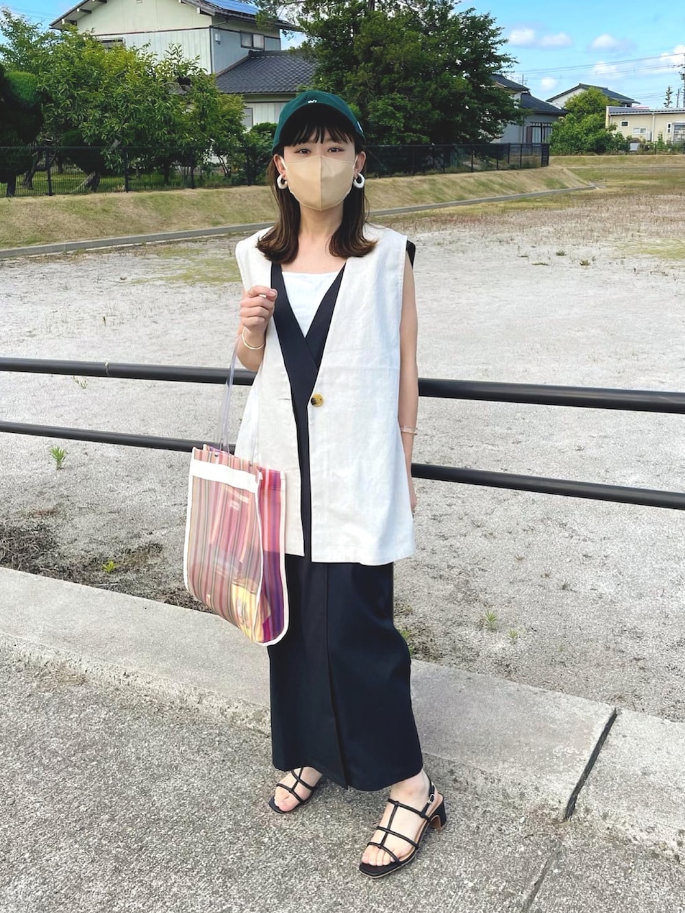 ブラック系のワンピース、ベージュ系のベスト、ホワイト系のトートバッグを着用したレディースの夏コーディネートの4枚目の写真