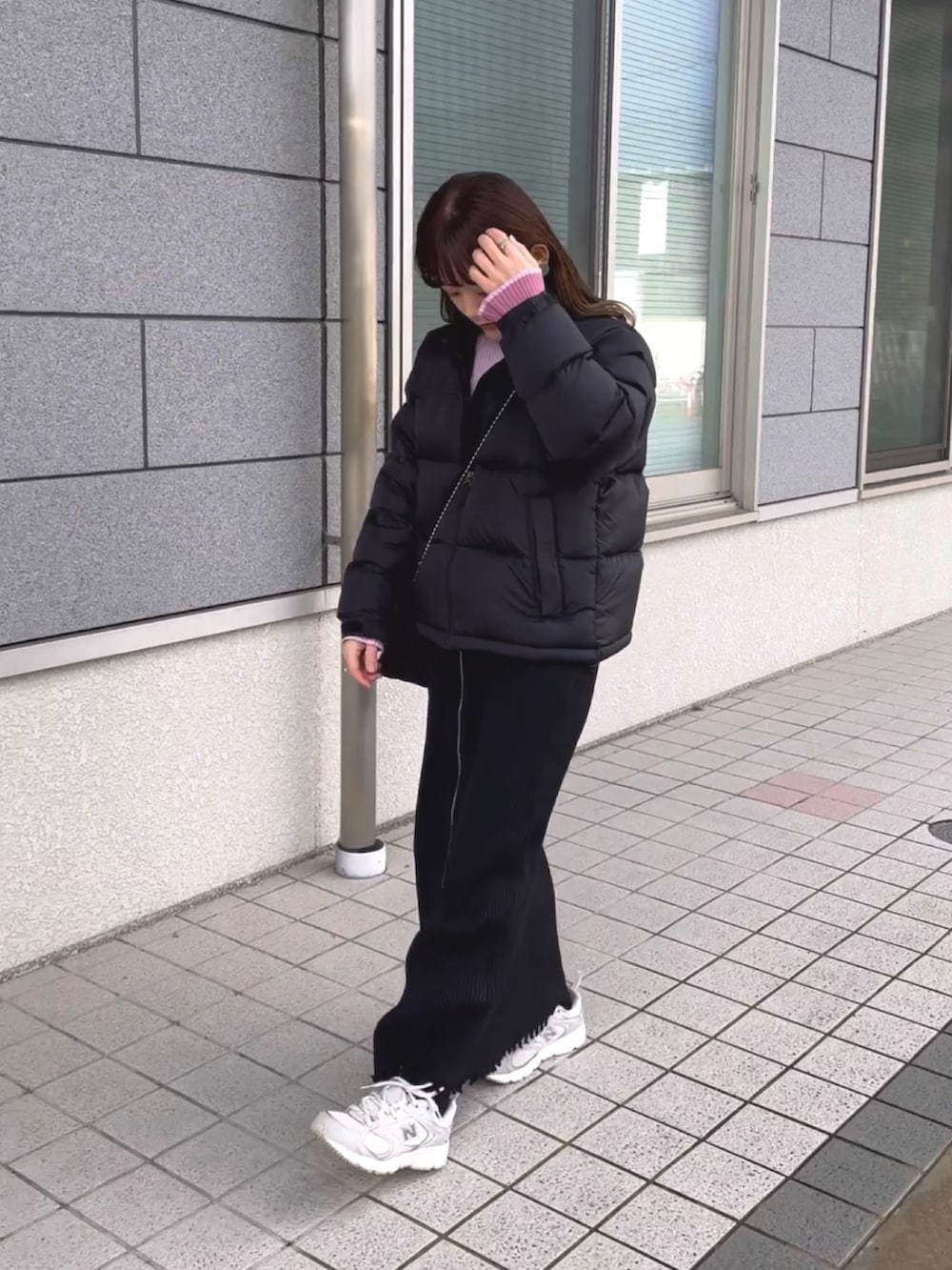 ブラック系のダウンジャケット/コート、ピンク系のニット/セーター、ブラック系のスカートを着用したレディースの冬コーディネートの3枚目の写真