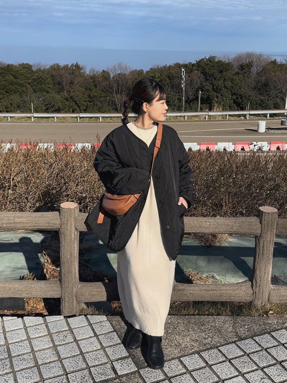 ブラック系のノーカラージャケット、ホワイト系のワンピース、ブラウン系のハンドバッグを着用したレディースの冬コーディネートの4枚目の写真