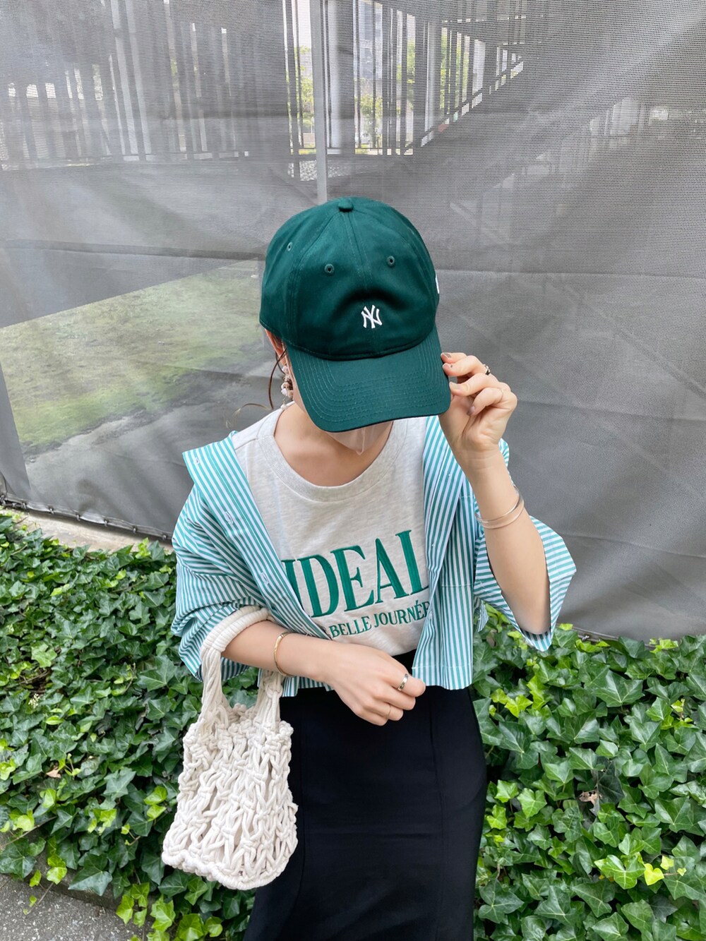 グリーン系のシャツ/ブラウス、ブラック系のスカート、ホワイト系のハンドバッグを着用したレディースの夏コーディネートの3枚目の写真