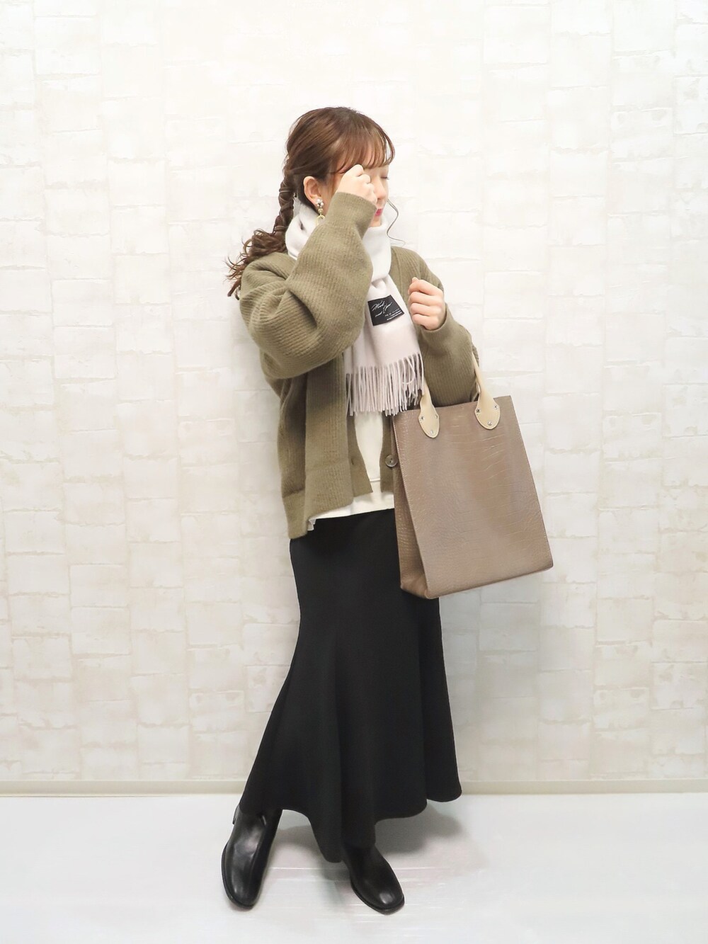 ブラウン系のトートバッグ、ブラウン系のカーディガン/ボレロ、ホワイト系のスウェットを着用したレディースの冬コーディネートの4枚目の写真