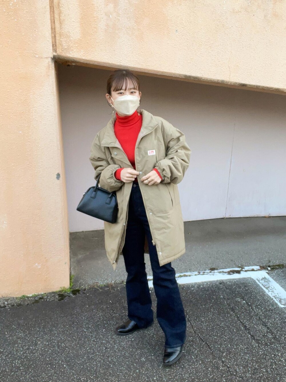 ベージュ系のダウンジャケット/コート、レッド系のトップス、ブルー系のデニムパンツを着用したレディースの冬コーディネートの2枚目の写真