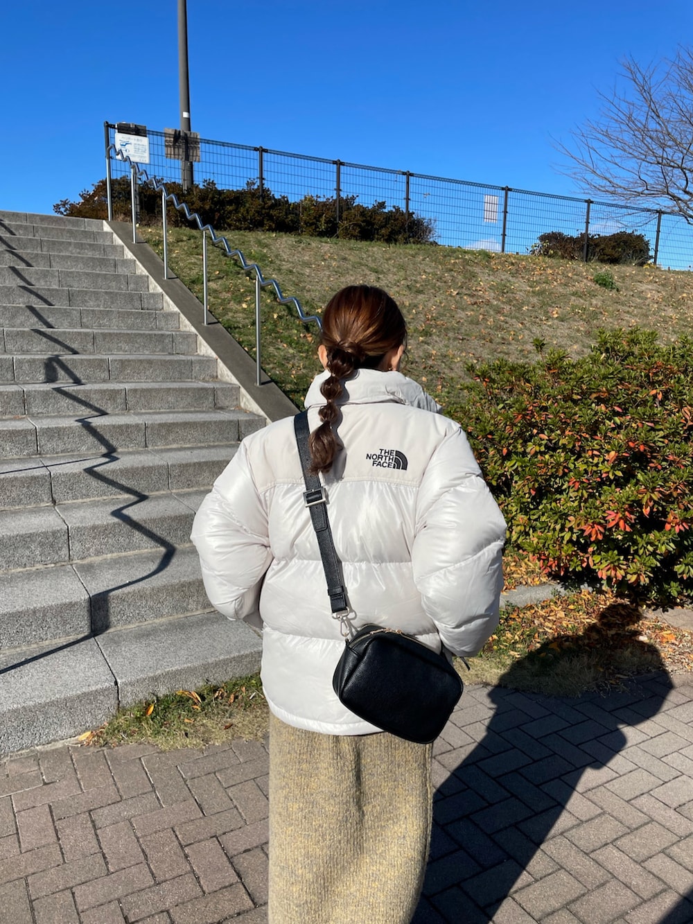 ホワイト系のダウンジャケット/コート、イエロー系のワンピース、ブラック系のブーツを着用したレディースの冬コーディネートの4枚目の写真