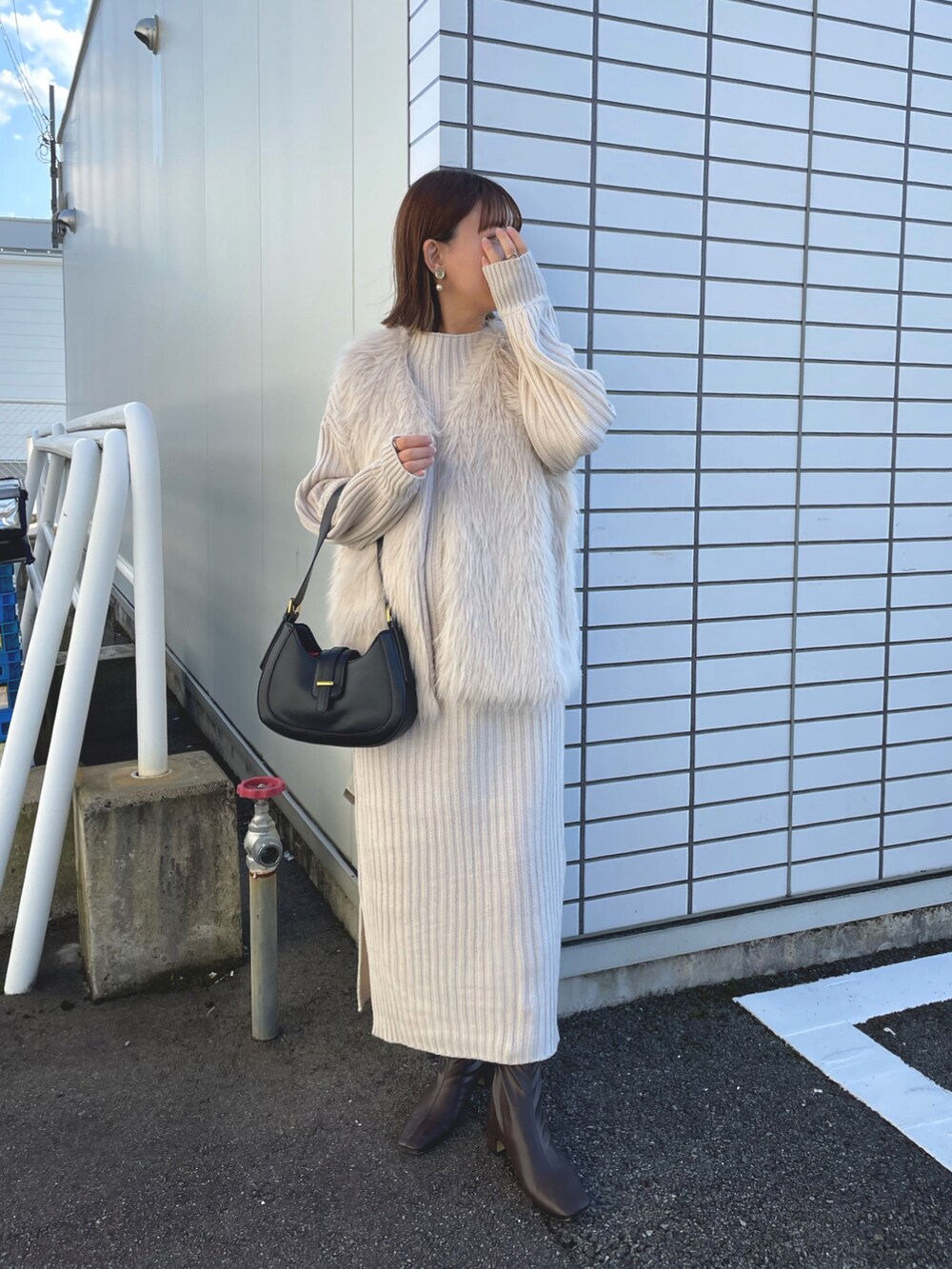 ホワイト系のベスト、ホワイト系のワンピース/ドレス、ブラック系のバッグを着用したレディースの秋コーディネートの2枚目の写真