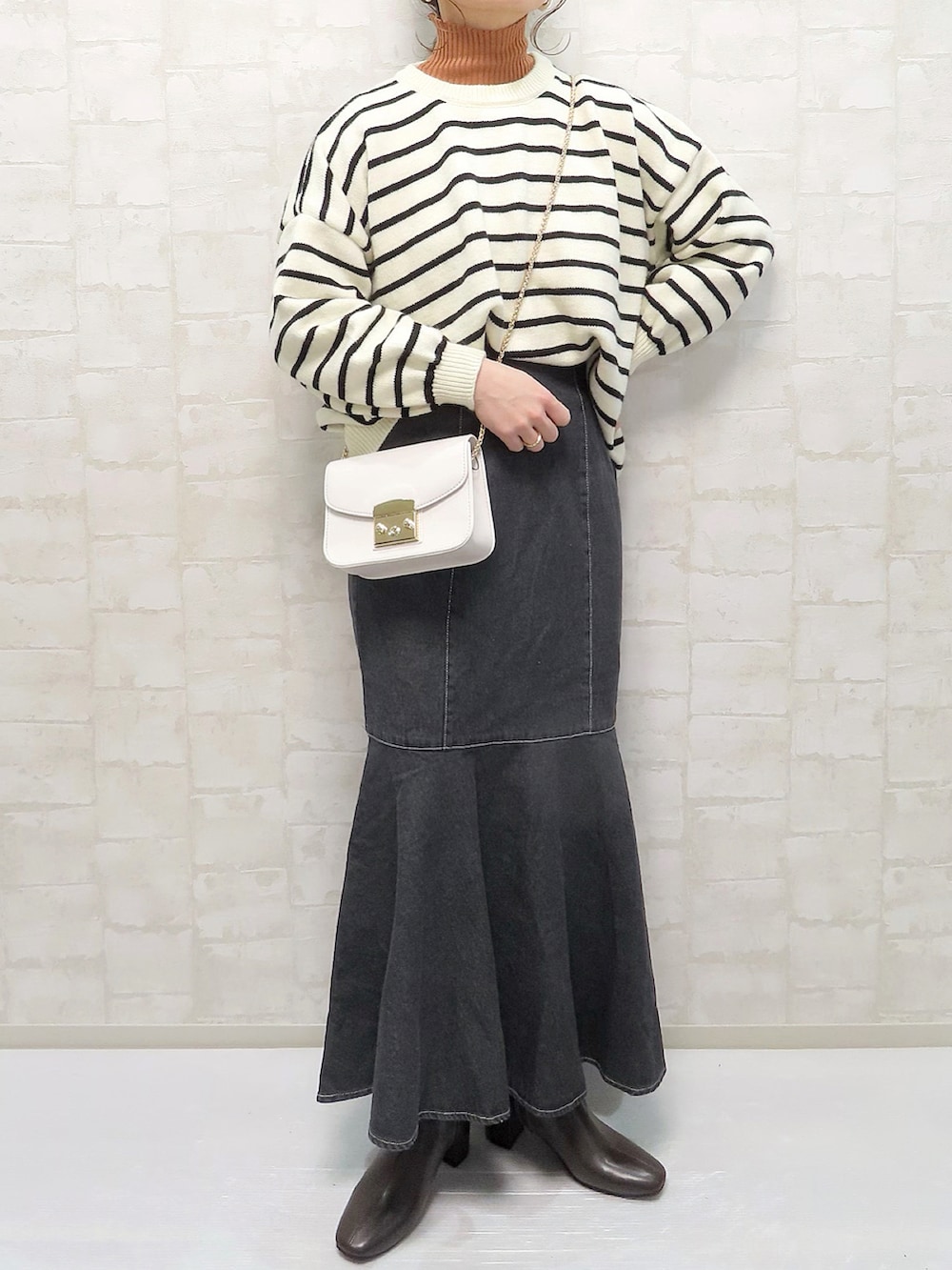 ホワイト系のニット/セーター、オレンジ系のニット/セーター、ブラック系のデニムスカートを着用したレディースの冬コーディネートの3枚目の写真