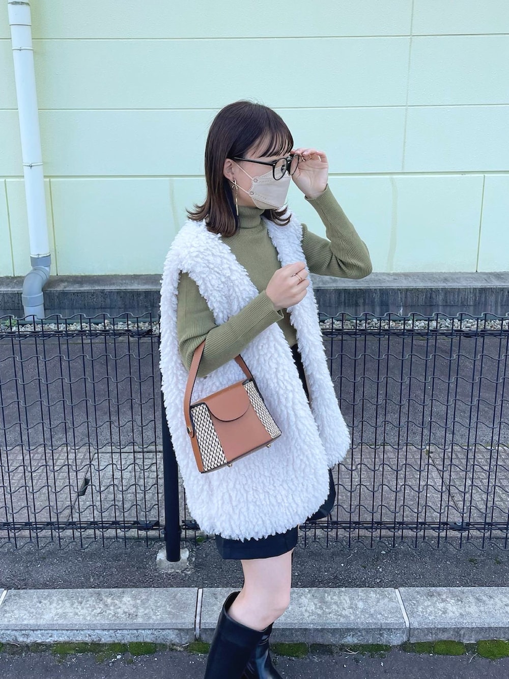 ホワイト系のベスト、グリーン系のニット/セーター、ブラック系のスラックスを着用したレディースの秋コーディネートの3枚目の写真