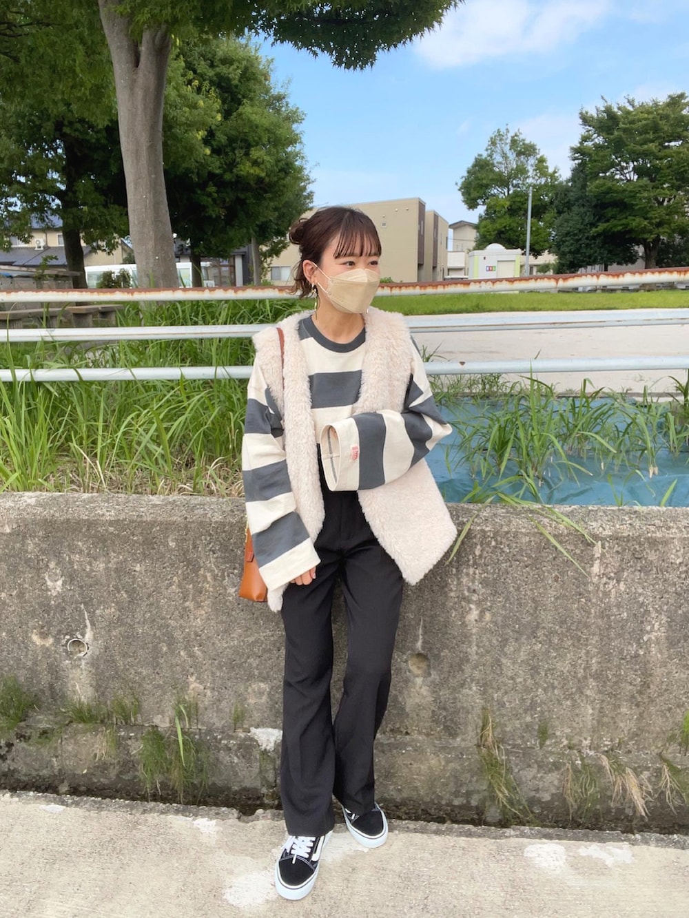 グリーン系のTシャツ/カットソー、グレー系のベスト、ブラック系のスラックスを着用したレディースの秋コーディネートの2枚目の写真