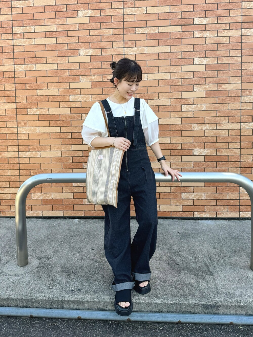 ホワイト系のシャツ/ブラウス、ブラック系のオールインワン・サロペット、ベージュ系のトートバッグを着用したレディースの夏コーディネートの2枚目の写真