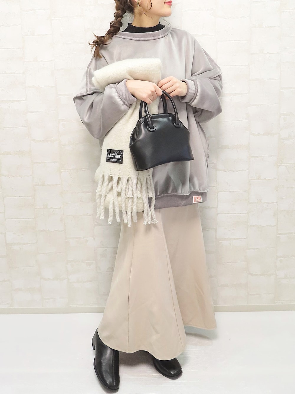 グレー系のスウェット、ブラック系のニット/セーター、ベージュ系のスカートを着用したレディースの冬コーディネートの3枚目の写真