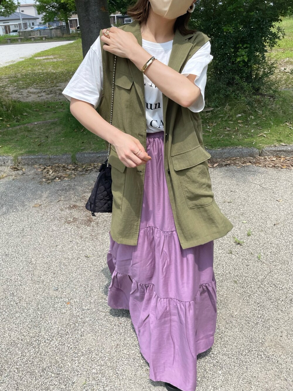 パープル系のスカート、ホワイト系のTシャツ/カットソー、ブラック系のサンダルを着用したレディースの夏コーディネートの2枚目の写真