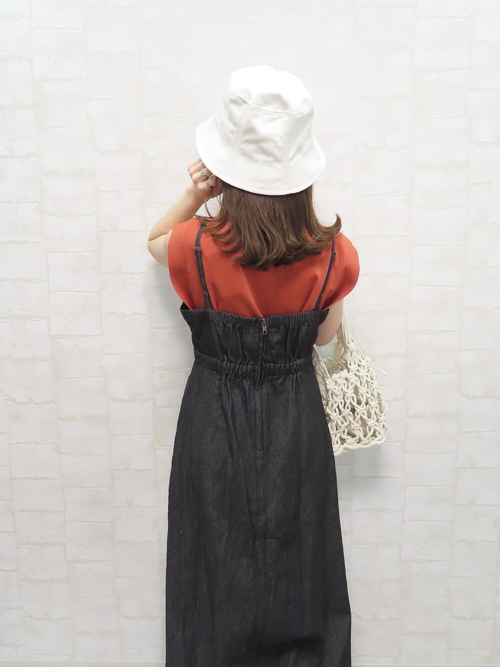 ブラック系のワンピース、オレンジ系のニット/セーター、ホワイト系のハットを着用したレディースの春コーディネートの3枚目の写真