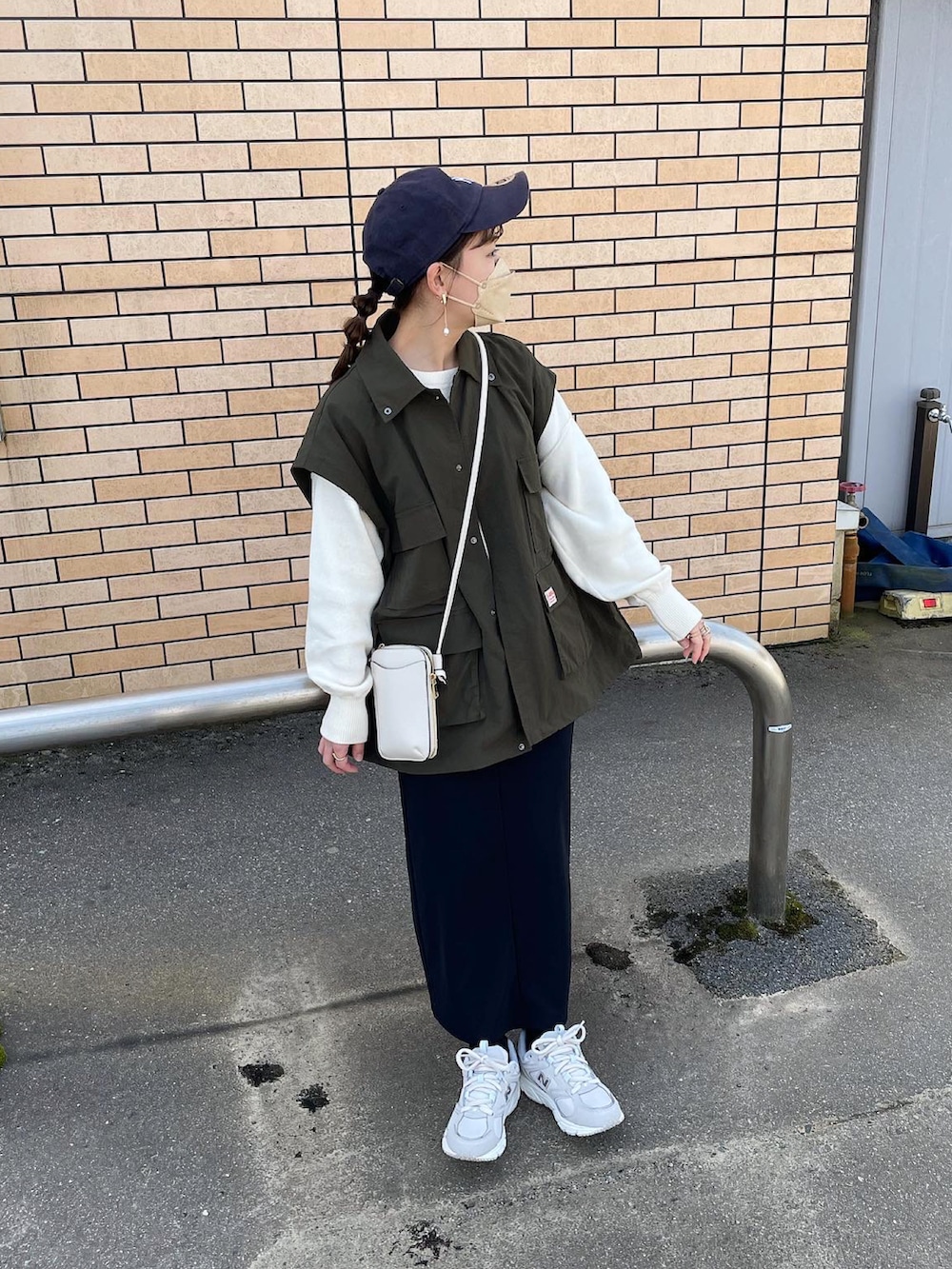 グリーン系のマウンテンパーカー、ホワイト系のニット/セーター、ブラック系のスカートを着用したレディースの春コーディネートの4枚目の写真