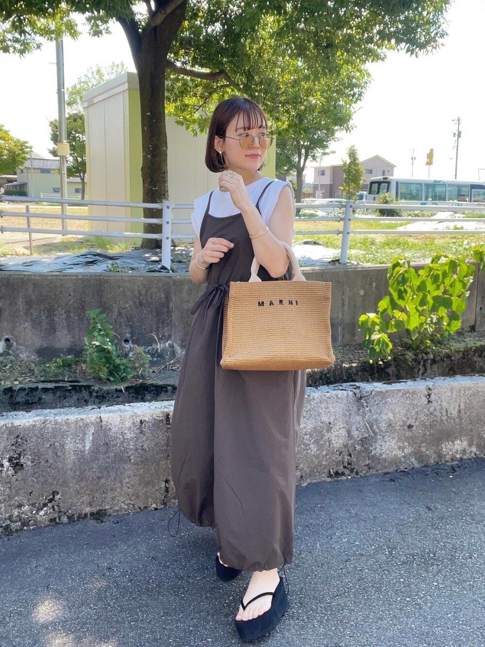 ブラウン系のワンピース/ドレス、ホワイト系のTシャツ/カットソー、ベージュ系のショルダーバッグを着用したレディースの夏コーディネートの2枚目の写真