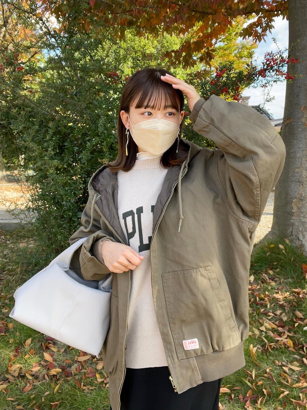 グリーン系のブルゾン、ホワイト系のニット/セーター、ベージュ系のバッグを着用したレディースの秋コーディネートの4枚目の写真