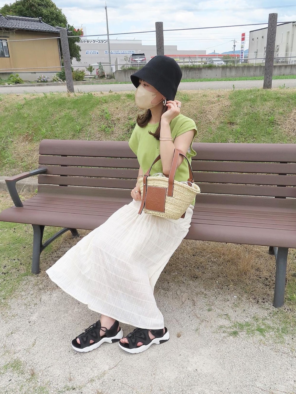 グリーン系のTシャツ/カットソー、ホワイト系のスカート、ベージュ系のかごバッグを着用したレディースの夏コーディネートの2枚目の写真