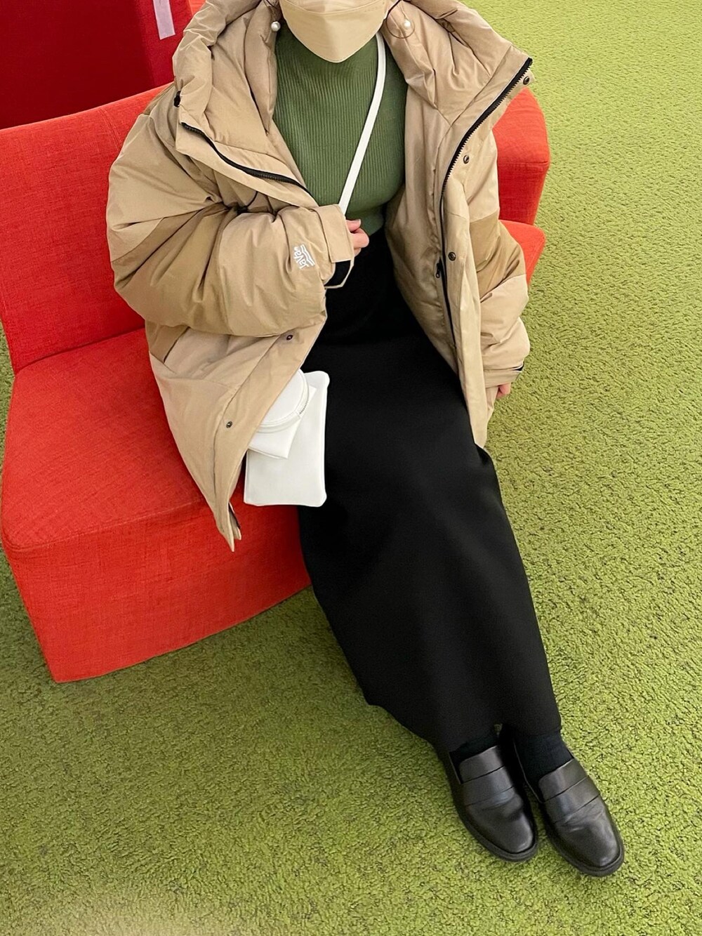 ベージュ系のダウンジャケット/コート、グリーン系のニット/セーター、ブラック系のスカートを着用したレディースの冬コーディネートの5枚目の写真