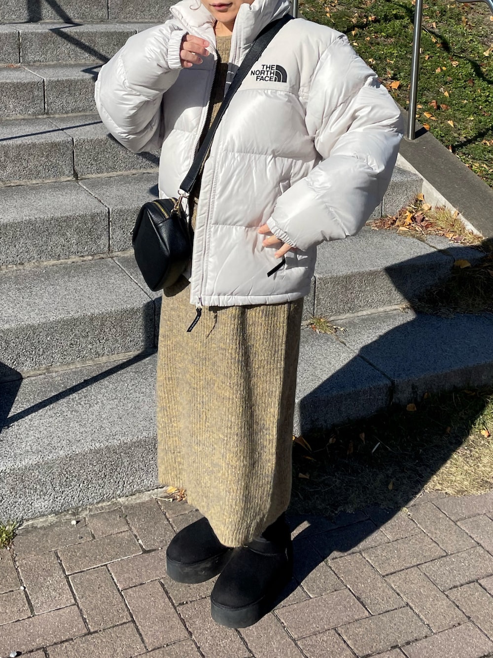 ホワイト系のダウンジャケット/コート、イエロー系のワンピース、ブラック系のブーツを着用したレディースの冬コーディネートの3枚目の写真