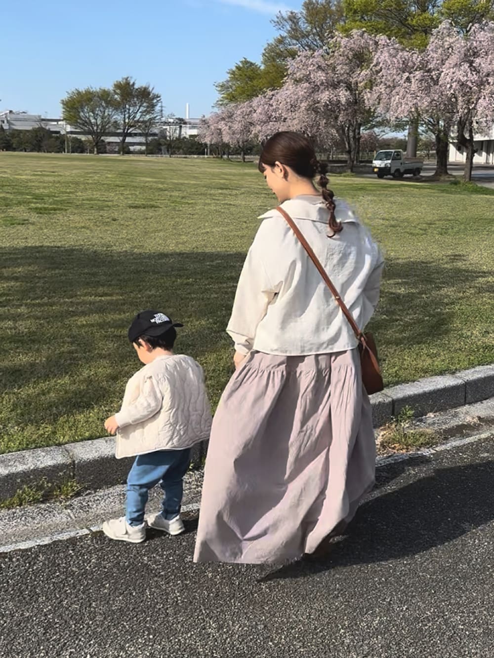 ベージュ系のワンピース、ブラウン系のショルダーバッグ、ブラック系のスニーカーを着用したレディースの春コーディネートの2枚目の写真