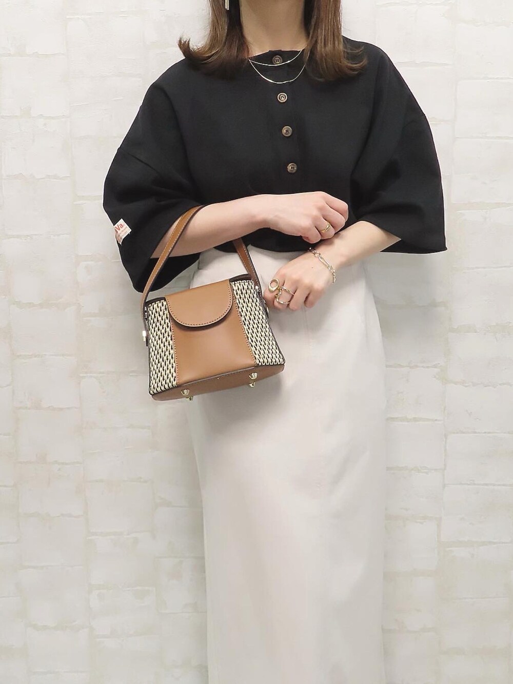 ブラック系のTシャツ/カットソー、ホワイト系のスカート、ゴールド系のネックレスを着用したレディースの春コーディネートの2枚目の写真