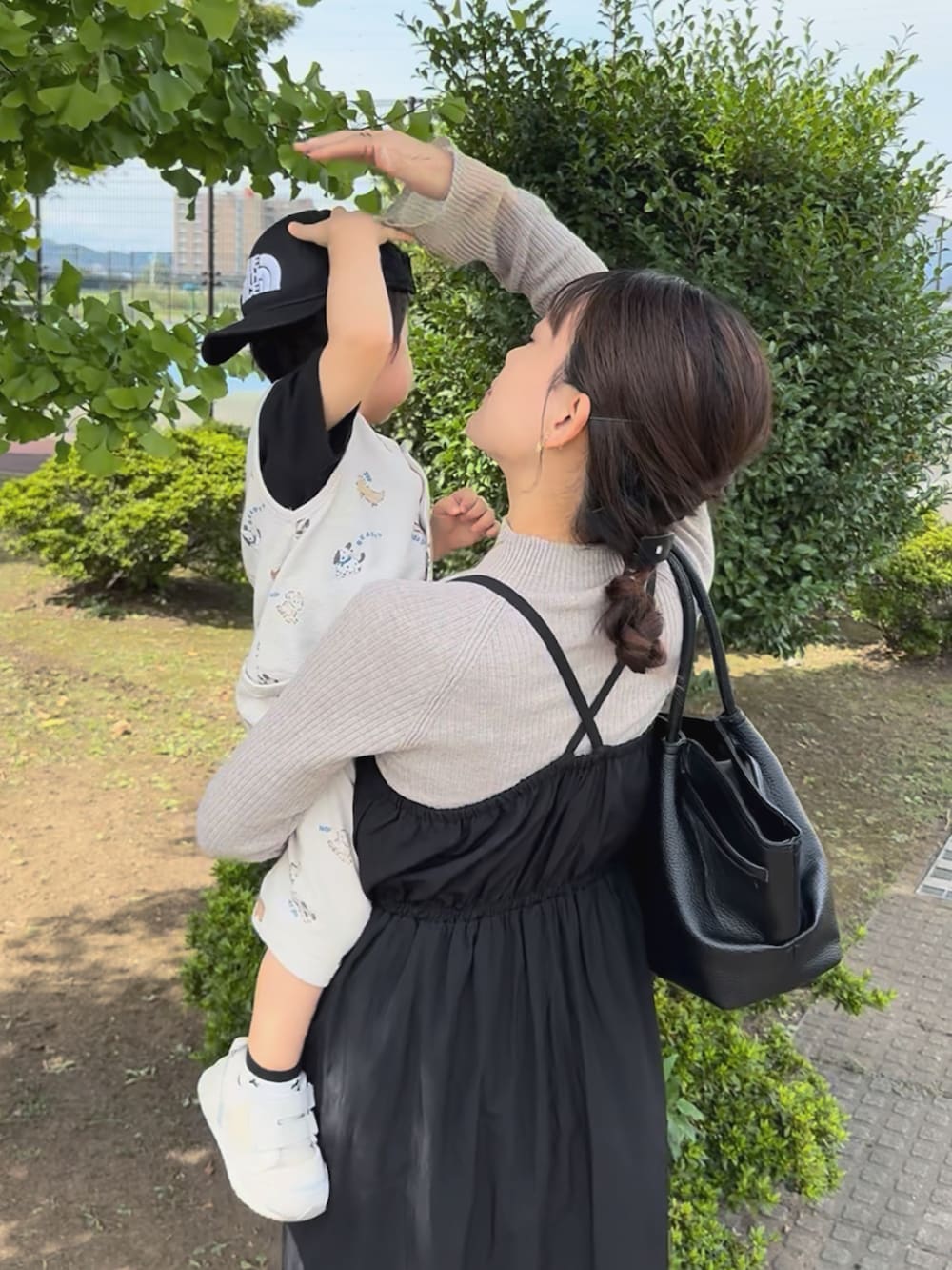 ブラウン系のニット/セーター、ブラック系のワンピース/ドレス、ブラック系のバッグを着用したレディースの秋コーディネートの2枚目の写真