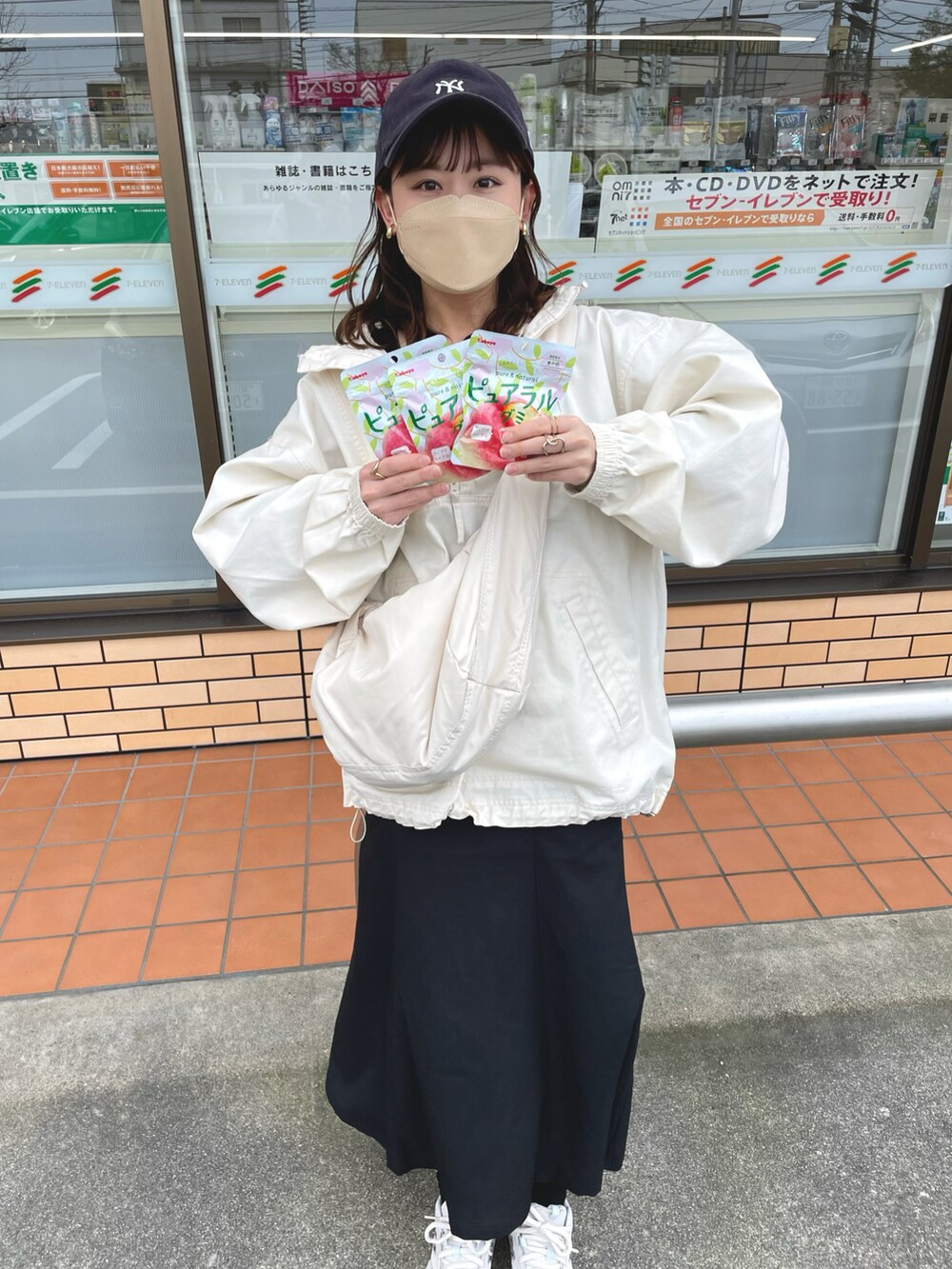 ホワイト系のパーカー、ブラック系のジャンパースカート、オレンジ系のキャミソールを着用したレディースの春コーディネートの2枚目の写真