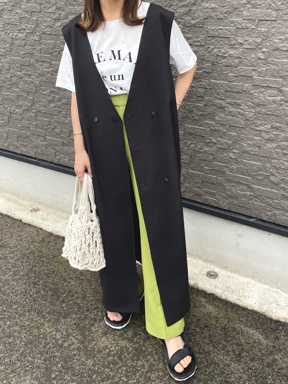 ブラック系のワンピース、ベージュ系のベスト、ホワイト系のトートバッグを着用したレディースの夏コーディネートの3枚目の写真